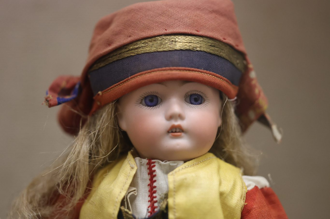 Porzellanpuppe mit blauen Augen, blonder Haar und traditioneller Kleidung.