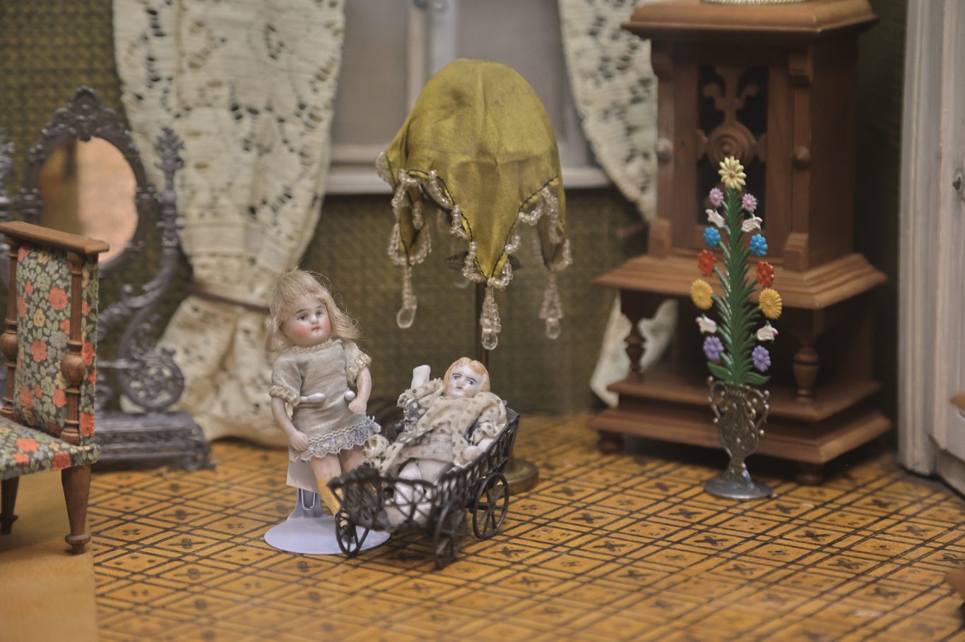 Zwei historische Puppen in einem Miniaturzimmer mit Möbeln und Dekorationen.