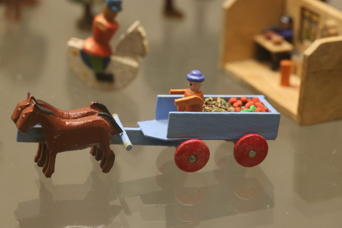 Ein kleiner Holzwagen mit einem Pferd, das einen Fahrerspielzeugmenschen zieht.