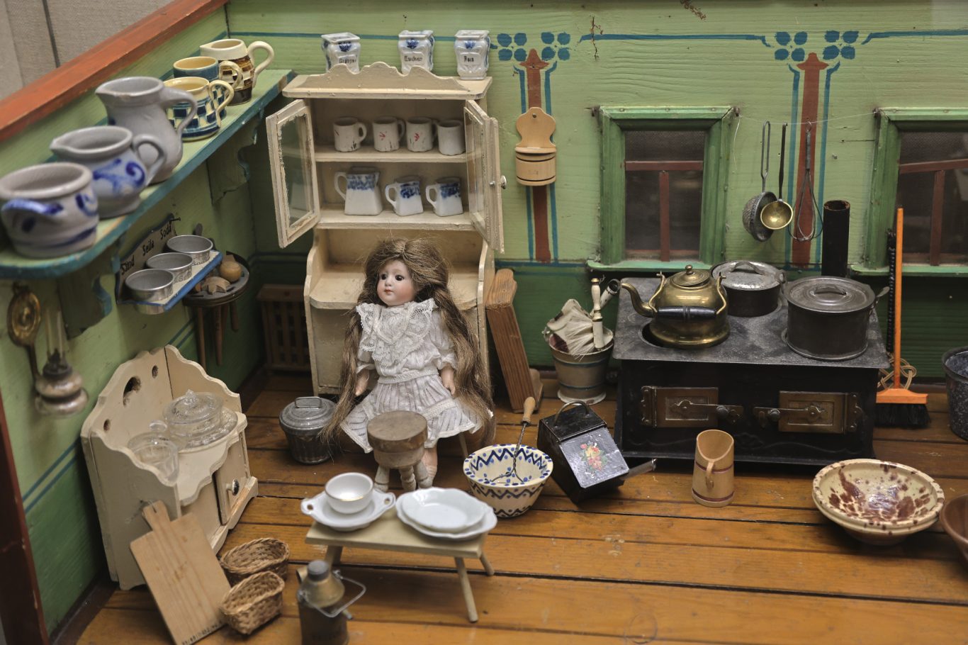 Historische Küchenszene mit einer Puppe, Töpfen und antiquierten Küchenutensilien.