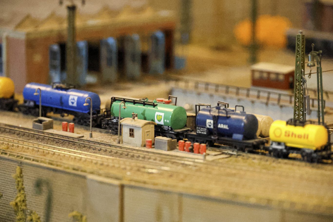 Modellbahnanlage mit mehreren Waggons in verschiedenen Farben auf Gleisen.