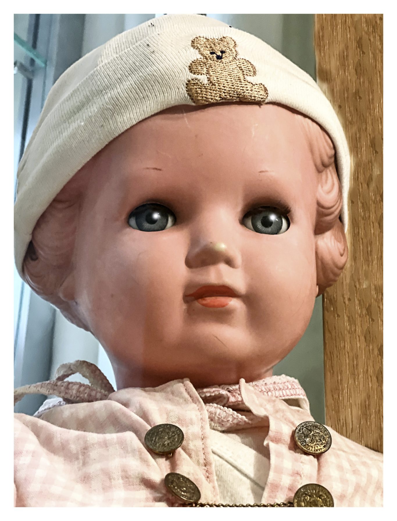 Porzellanpuppe mit blauen Augen, rosa Kleid und weißem Hut.