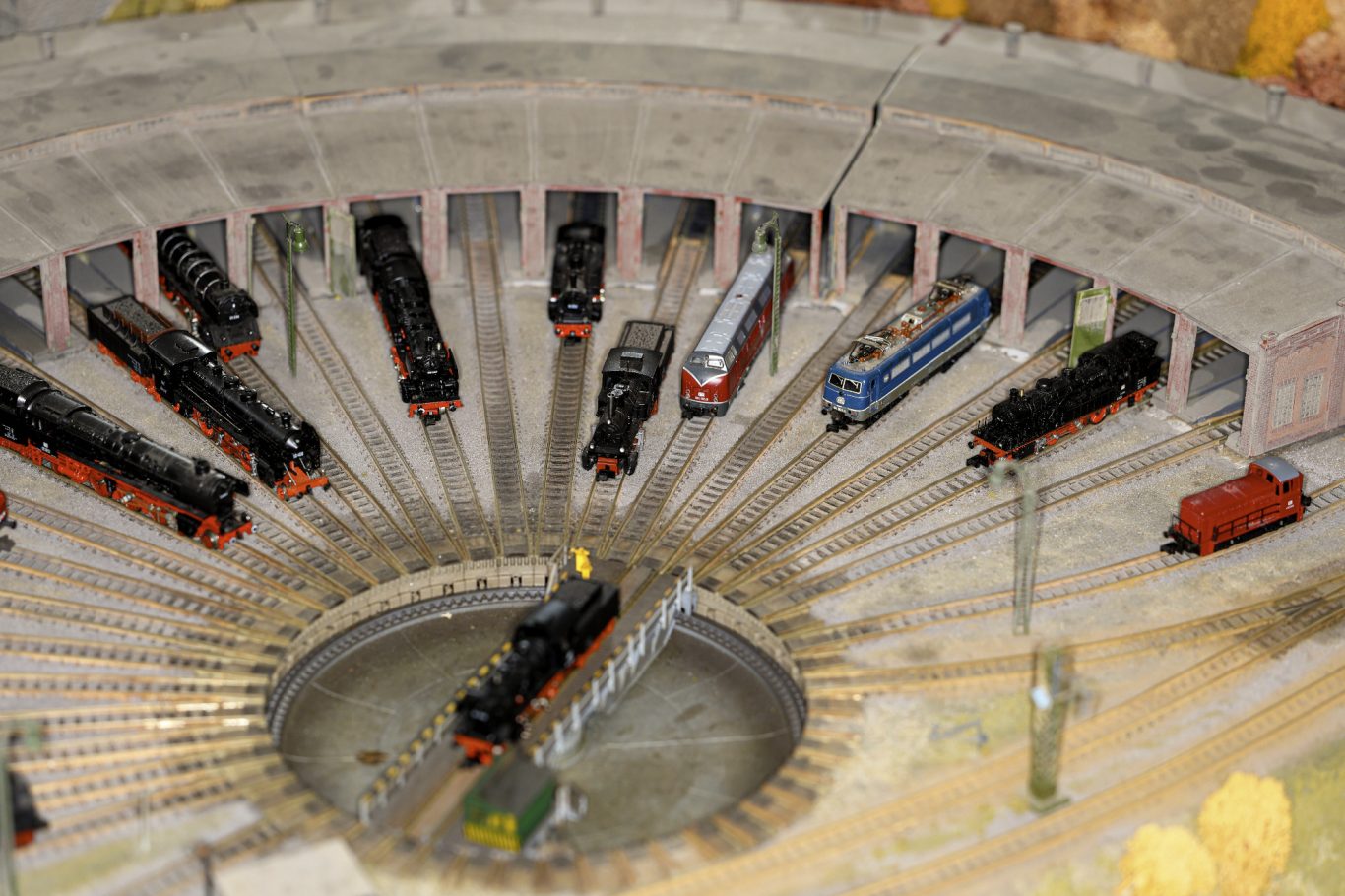 Modellbahnanlage mit mehreren Lokomotiven in einem Rundhaus angeordnet.